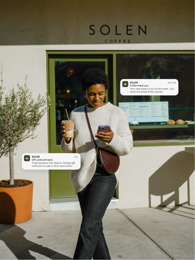 A guest leaving a coffee shop with her drink and phone